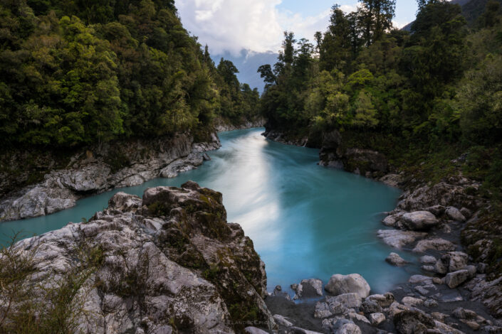 Blue River flowing between forest in New Zealand. Buy a canvas, framed or acrylic fine art print.