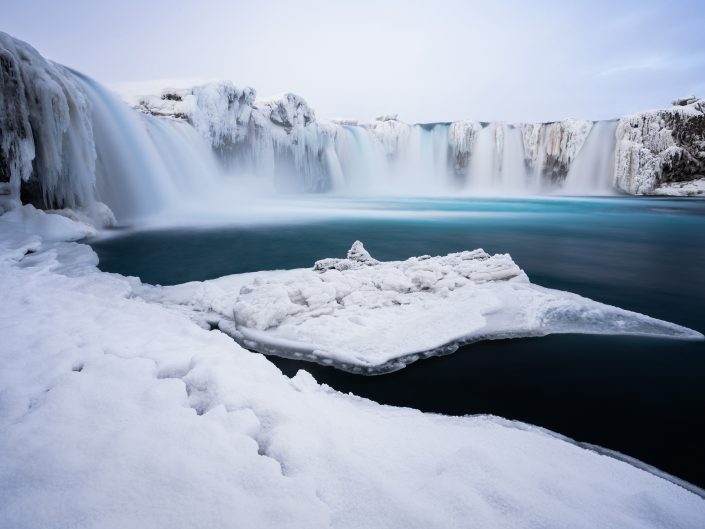 Long exposure photography of the frozen Godafoss (Waterfall of Gods) in the North of Iceland. Buy a canvas, framed or acrylic fine art print.