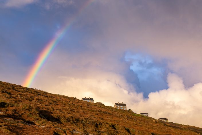 Rainbow and dramatic clouds over houses built on a hill on English Coast in Cornwall. Buy a canvas, framed or acrylic fine art print.