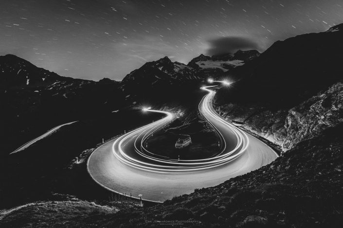 Buy a canvas, framed or acrylic fine art print. Black and white photo of light trails on one of alpine mountain passes with start trails and California campervan.